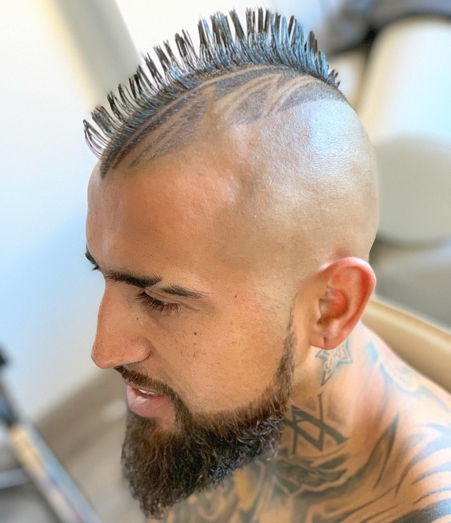 Dettaglio di un taglio con motivi rasati e barba curata