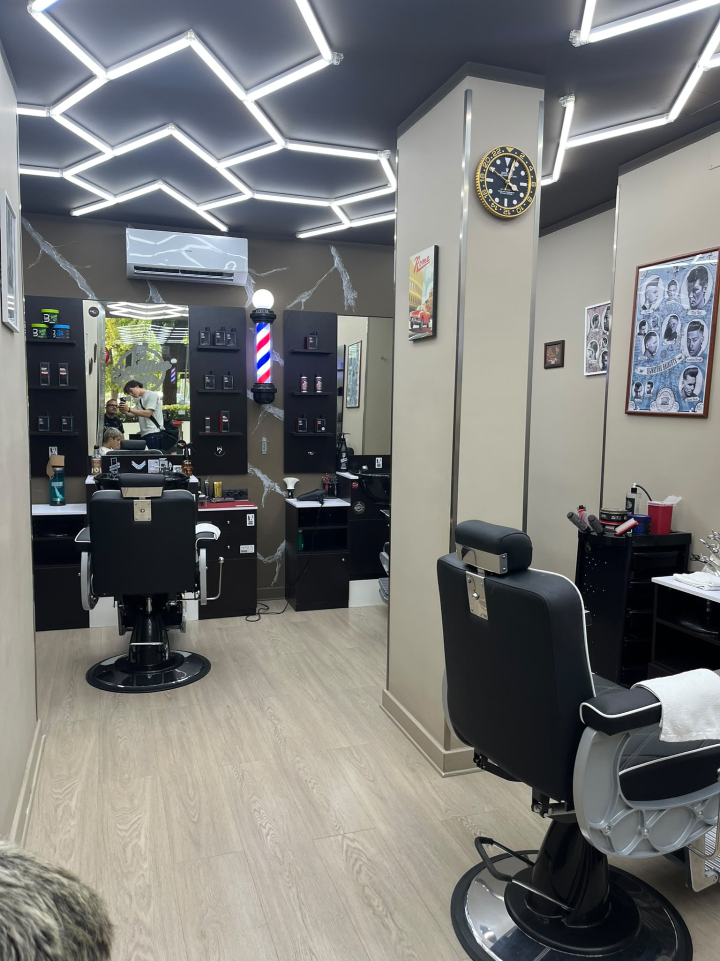 Interno di Schittino Barber Shop a Collegno, con poltrone da barbiere e luci geometriche a soffitto